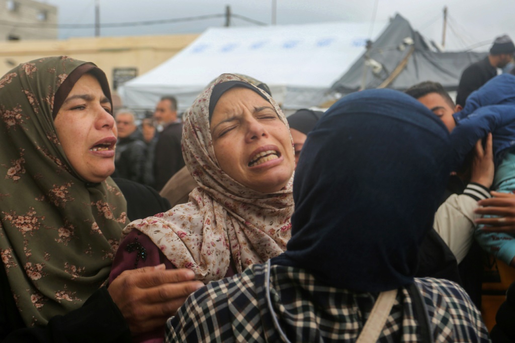 نساء فلسطينيات يبكون مقتل أقاربهن في غارة جوية إسرائيلية على دير البلح بغزة. (ا ف ب)