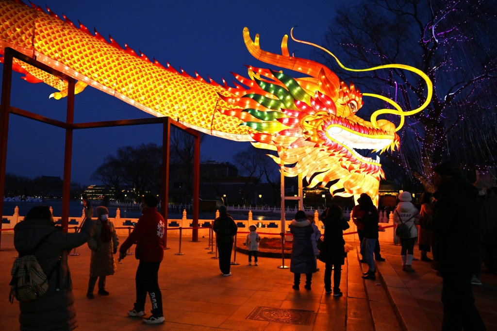 يتجمع الناس لإلقاء نظرة على شخصية تنين عملاقة في حديقة في بكين في 9 فبراير 2024، والذي يصادف عشية رأس السنة القمرية الجديدة للتنين. (ا ف ب)