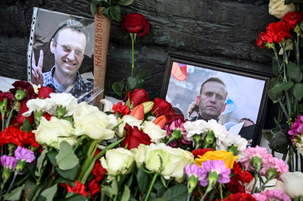 صور المعارض الروسي الراحل اليكسي نافالني قرب باقات من الورود أمام نصب ضحايا القمع السياسي في موسكو، في 17 شباط/فبراير 2024. (أ ف ب)   
