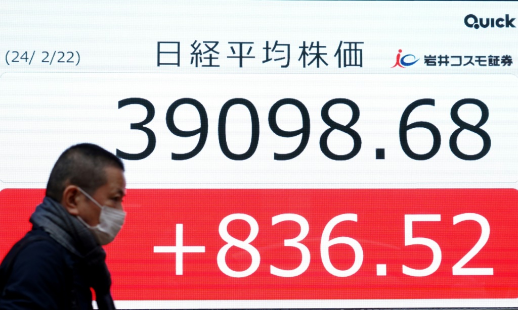رجل يمشي أمام شاشة تُظهر مستوى مؤشر نيكاي 225 الياباني عند الإغلاق في بورصة طوكيو في 22 شباط/فبراير 2024 (أ ف ب)   