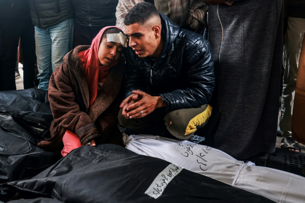 فتاة مصابة ورجل في مستشفى النجار برفح يبكون على جثث أقاربهم الذين قتلوا في القصف الإسرائيلي (ا ف ب)