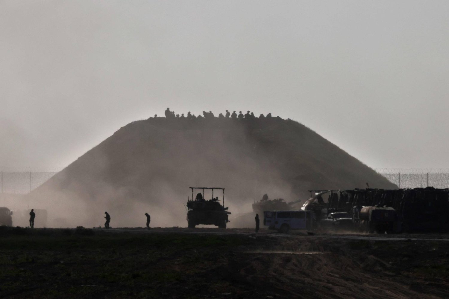 ناقلة جند إسرائيلية تغادر غزة (الاثنين) بينما يتجمع جنود قرب تلة متاخمة للقطاع (أ.ف.ب)