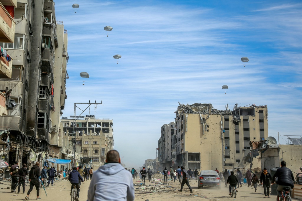 صورة مؤرخة في 1 آذار مارس 2024 لفلسطينيين يحاولون الحصول على مساعدات ترمى من الجو في مدينة غزة (ا ف ب)