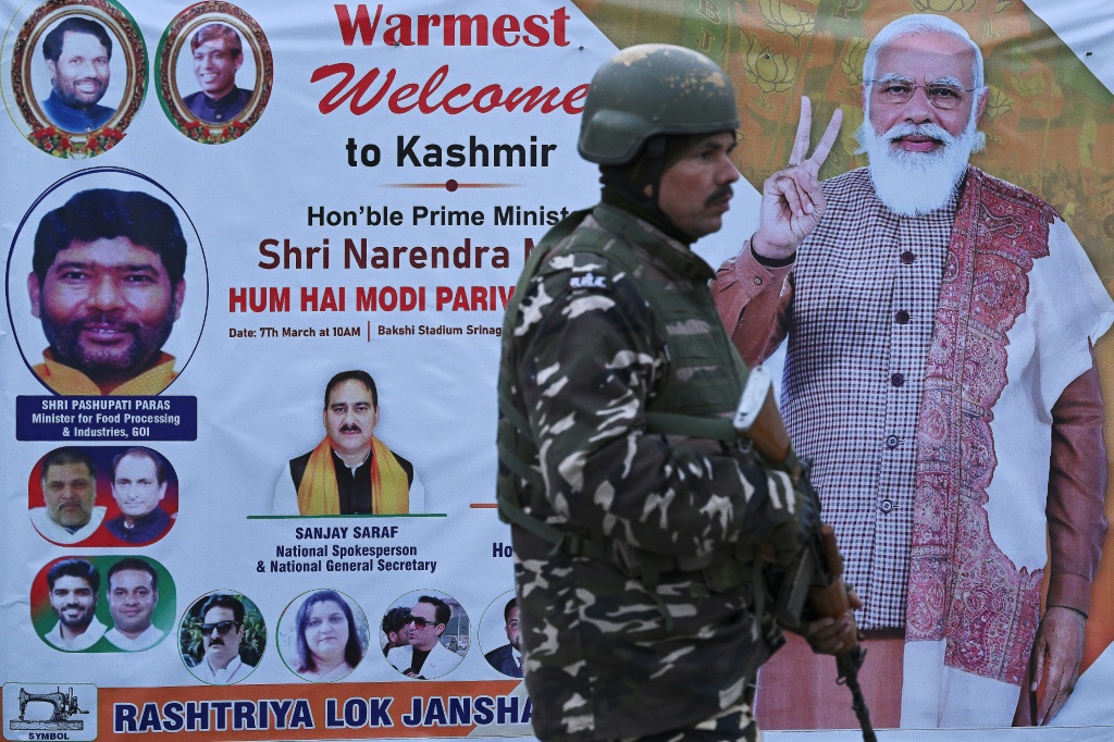 ضابط أمن هندي يقف للحراسة أمام ملصق عليه صورة رئيس الوزراء الهندي ناريندرا مودي في سريناجار (أ ف ب)   