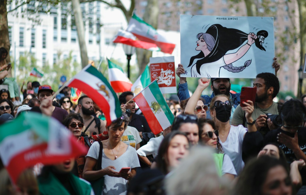 أشخاص يرفعون لافتات وأعلامًا إيرانية خلال تظاهرة في نيويورك تضامنًا مع النساء الإيرانيات في 16 أيلول/سبتمبر 2023 في الذكرى الأولى لوفاة الشابة مهسا أميني (أ ف ب)   
