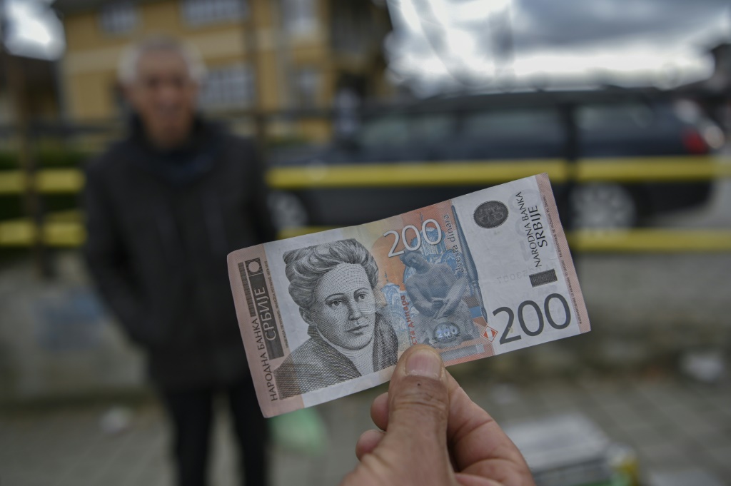 بائع متجول يحمل ورقة نقدية بالدينار الصربي في غراكانيتشا، كوسوفو (ا ف ب)   
