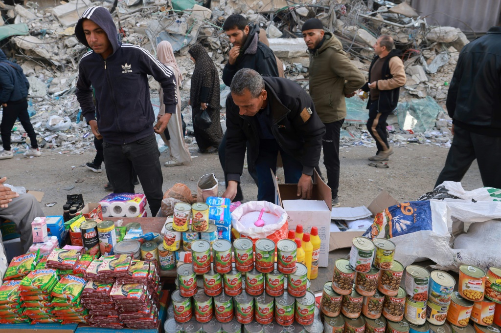 فلسطينيون يمرون أمام نصبات لبيع البضاعة اقيمت في أحد شوارع رفح جنوب قطاع غزة في 10 آذار/مارس 2024، فيما يستعد المسلمون لشهر رمضان المبارك وسط المعارك المستمرة بين إسرائيل وحركة حماس الفلسطينية (ا ف ب)