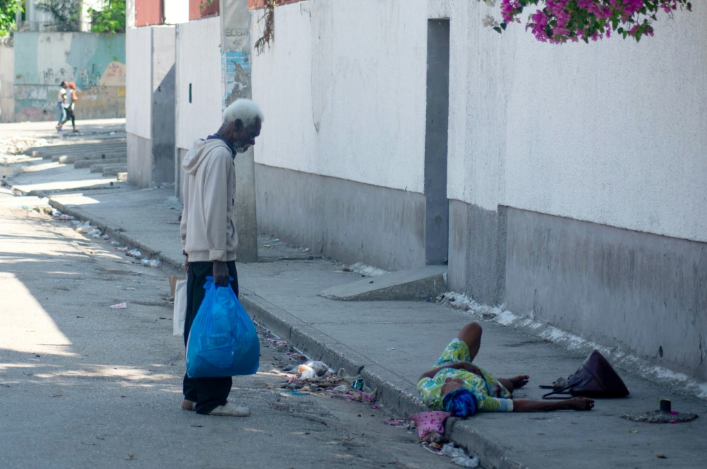 رجل يبذل قصارى جهده لمساعدة امرأة مسنة أصيبت بطلق ناري في قدمها، في بورت أو برنس، هايتي، في 9 مارس 2024. (أ ف ب)   