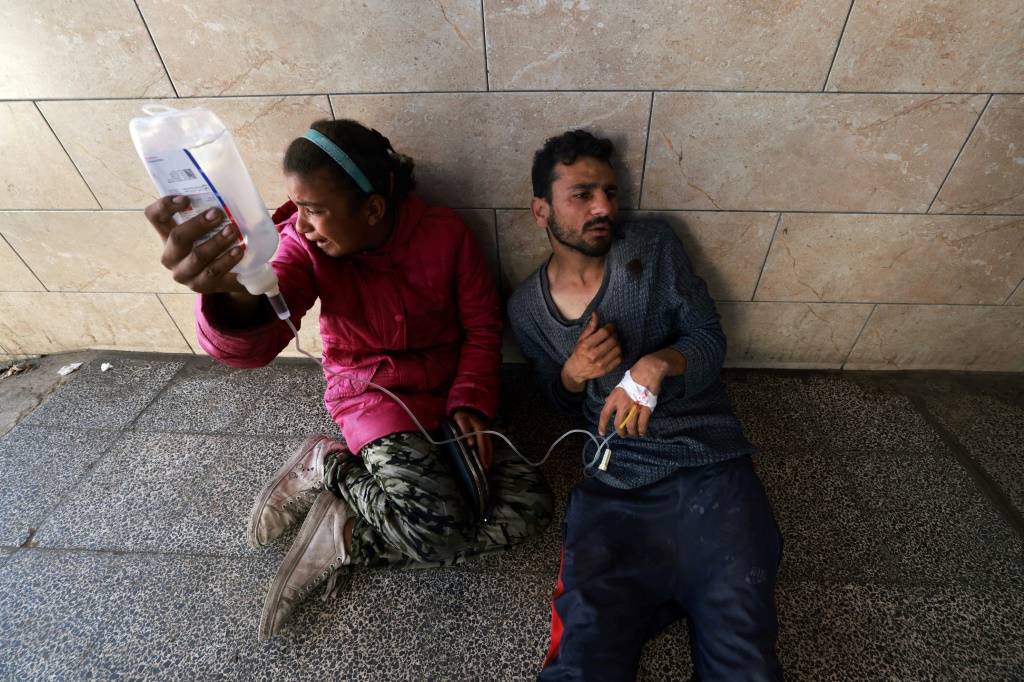 فتاة فلسطينية تبكي وهي تساعد جريحًا خارج مستشفى النجار في رفح، جنوب قطاع غزة، في أعقاب غارات إسرائيلية في 13 آذار/مارس 2024، في ظل الحرب المستمرة بين إسرائيل وحركة حماس (ا ف ب)