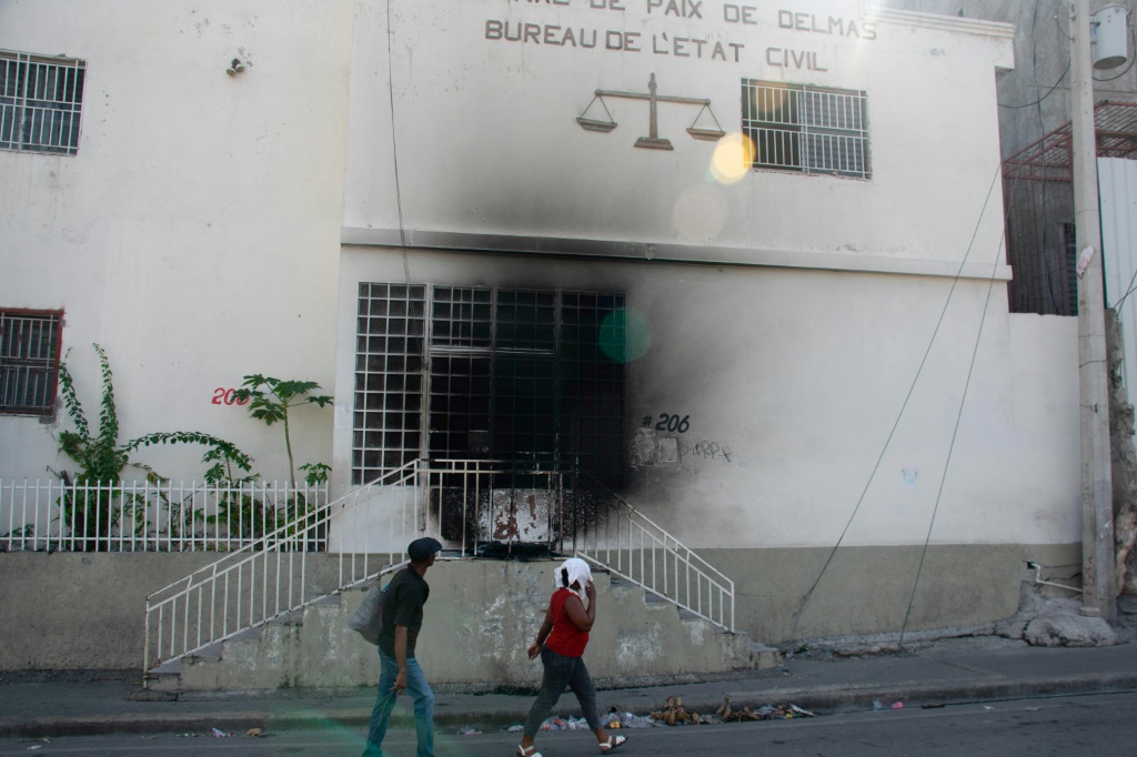 سكان يمرّون أمام محكمة بورت أو برنس التي أحرقتها العصابات المسلّحة، في السادس من آذار/مارس 2024 (ا ف ب)