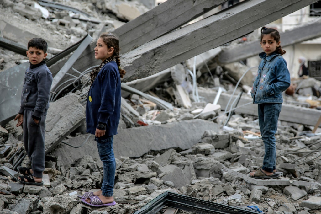 أطفال فلسطينيون وسط انقاض مبنى دمرته ضربة إسرائيلية في حي الرمال في غزة في 16 آذار/مارس 2024 (ا ف ب)