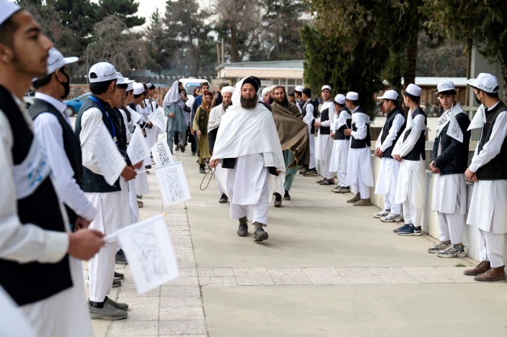 تلاميذ أفغان يحملون أعلام طالبان خلال استقبال مسؤولين محليين في حفل بمناسبة بدء الموسم الدراسي في مدرسة "أماني" في كابول في 20 آذار/مارس 2024 (أ ف ب)   