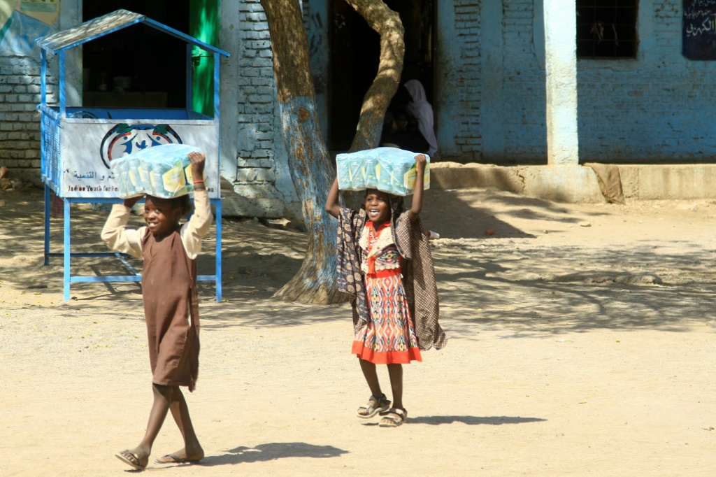 أطفال سودانيون يحملون مساعدات غذائية في مدرسة تضم نازحين قرب القضارف في السودان في السادس من آذار/مارس 2024 (أ ف ب)   