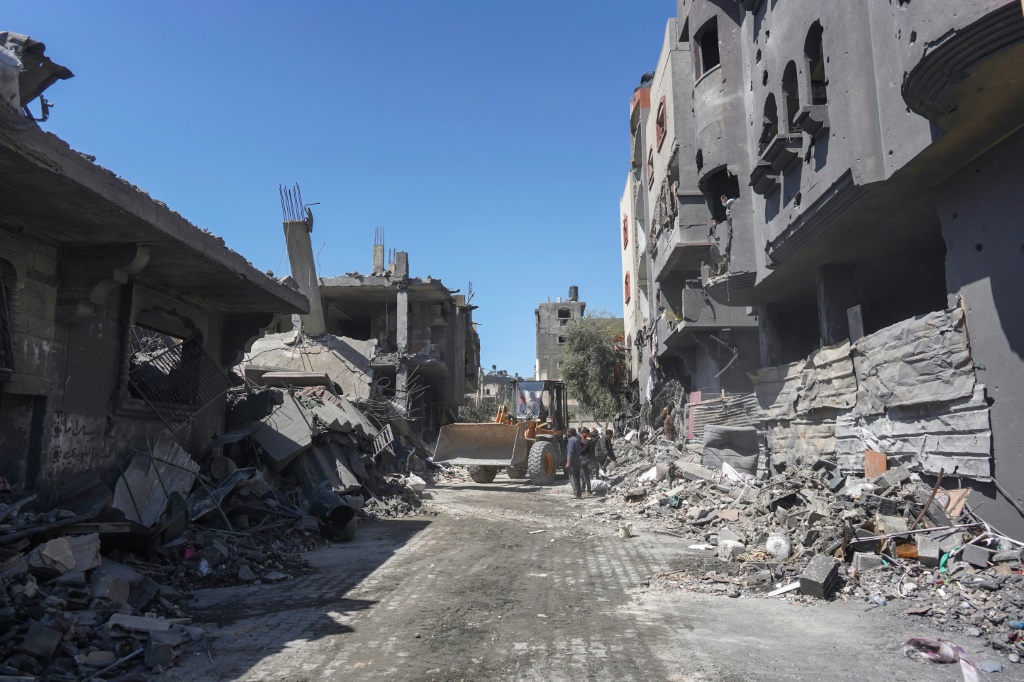 فلسطينيون يزيلون الركام بجرافة في أعقاب قصف إسرائيلي خلال الليل أصاب منزل عائلة الهباش في مخيم النصيرات للاجئين في وسط قطاع غزة في 20 آذار/مارس 2024 (ا ف ب)