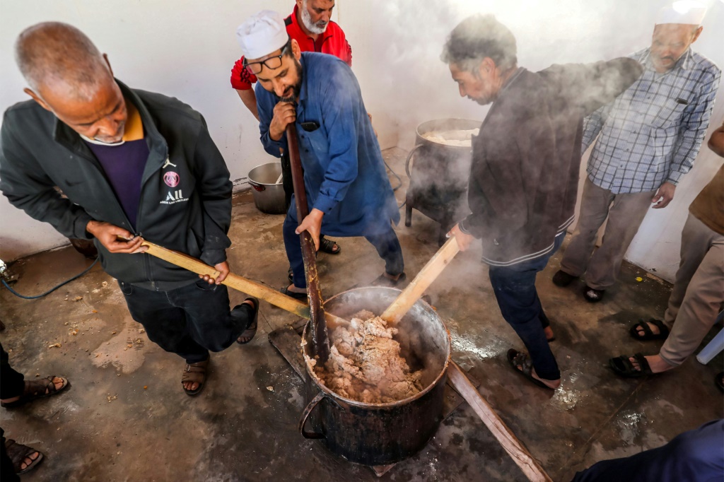 متطوعون يحضّرون حصصاً من طبق البازين الليبي التقليدي في تاجوراء بشرق العاصمة الليبية طرابلس في 13 آذار/مارس 2024. (ا ف ب)