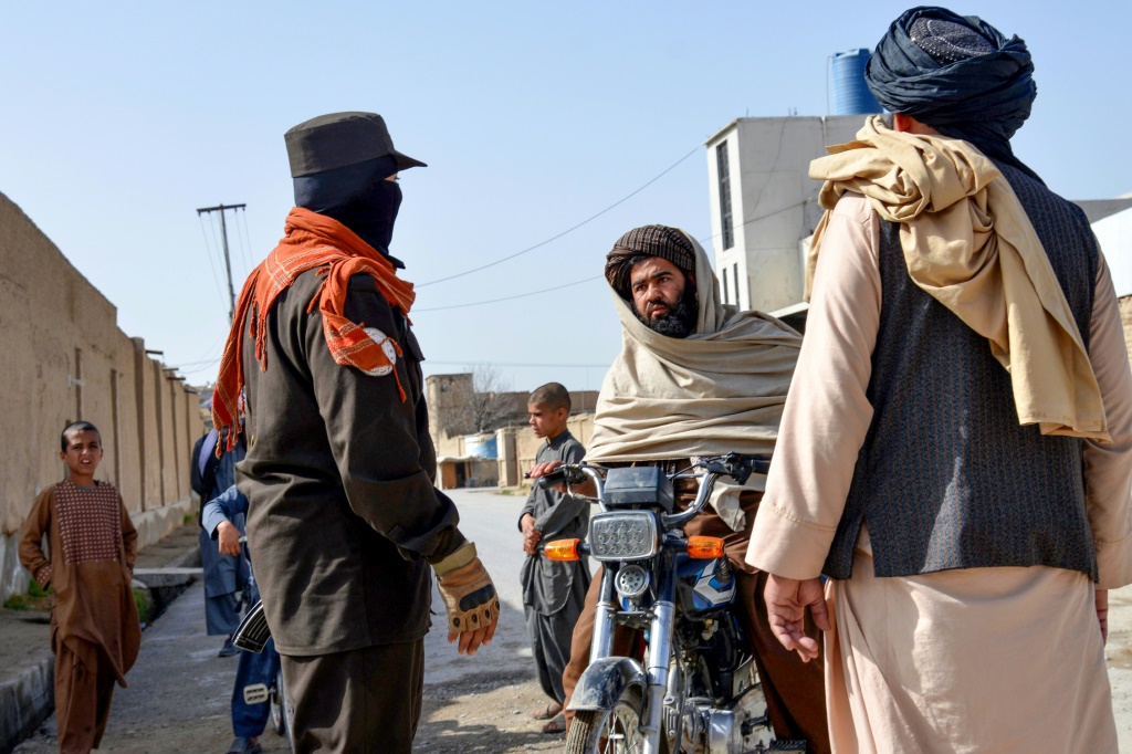 عنصر أمن أفغاني يفتش شخصا على متن دراجة نارية في موقع الهجوم الانتحاري في قندهار بتاريخ 21 آذار/مارس 2024 (ا ف ب)