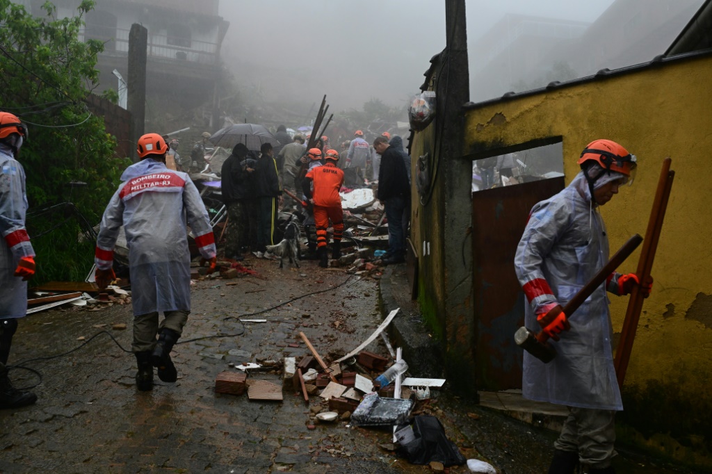 أفراد من الدفاع المدني ورجال الإطفاء والجيران يعملون على إنقاذ الضحايا في المنطقة المتضررة من الأمطار الغزيرة في بتروبوليس، البرازيل (أ ف ب)   