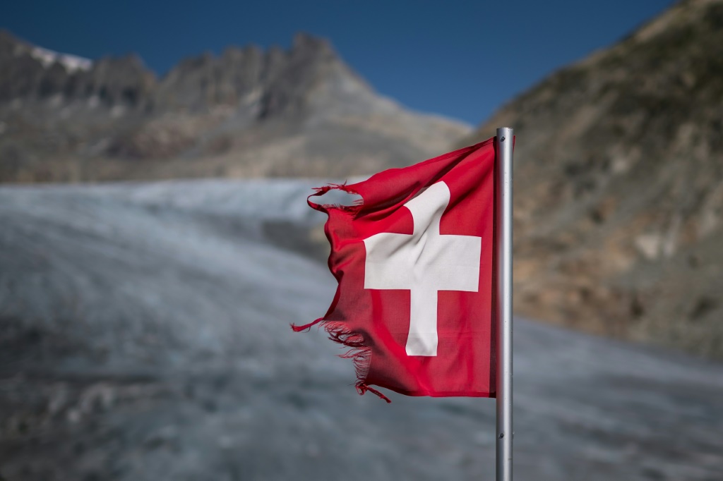 صورة ملتقطة في 24 آب/أغسطس 2023 في الألب السويسرية تظهر علم سويسرا قرب نهر رون الجليدي حيث يُسجل ذوبان متسارع للجليد. (ا ف ب)
