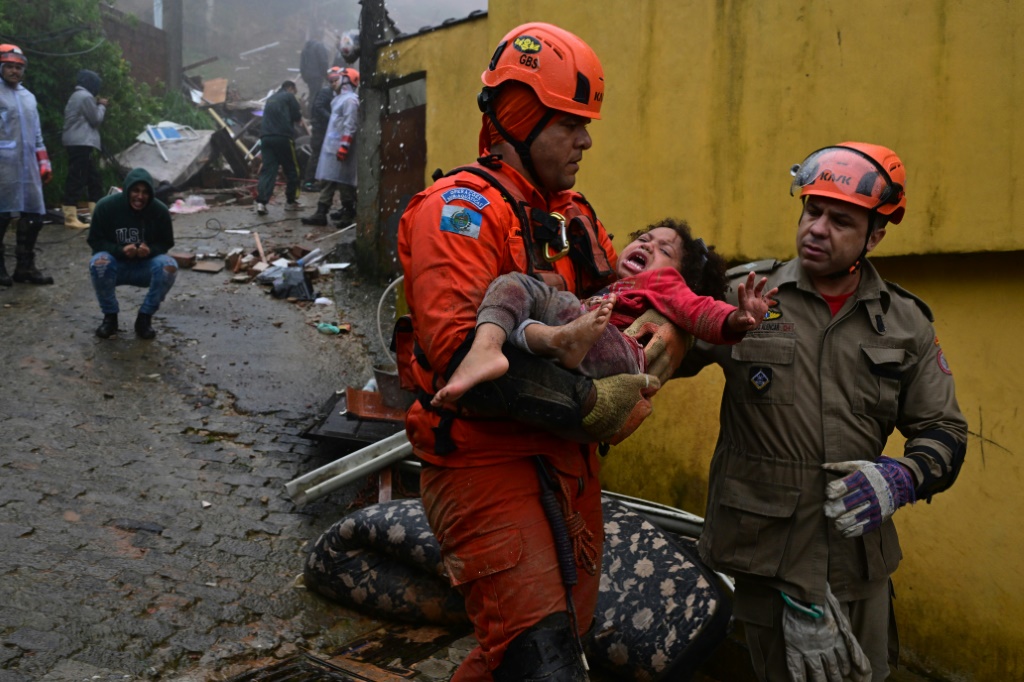 صورة مؤرخة في 23 آذار/مارس 2024 لعنصر إنقاذ يحمل طفلة تم إنقاذها في بتروبوليس البرازيلية بعدما بقيت 16 ساعة تحت انقاض منزلها الذي دمّرته الامطار الغزيرة. (ا ف ب)