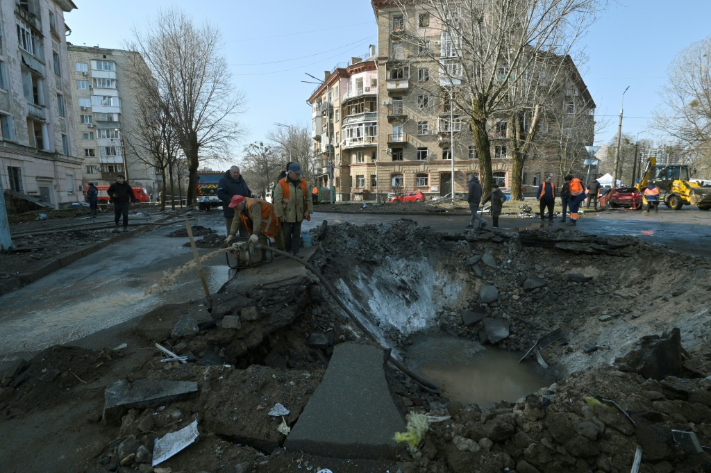 عمال بلدية يصلحون أضرارا ناجمة عن سقوط صاروخ في كييف في 21 آذار/مارس 2024 (ا ف ب)