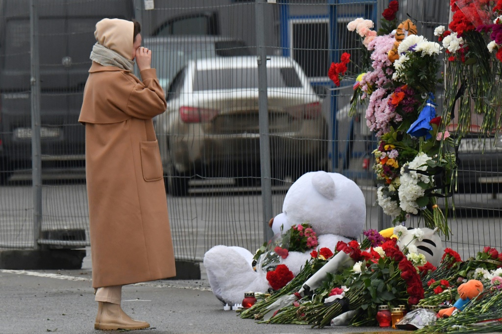 صورة مؤرخة في 23 آذار/مارس 2024 لامرأة أمام نصب تذكاري في موقه الهجوم على صالة كروكوس سيتي هول في ضاحية موسكو. (ا ف ب)