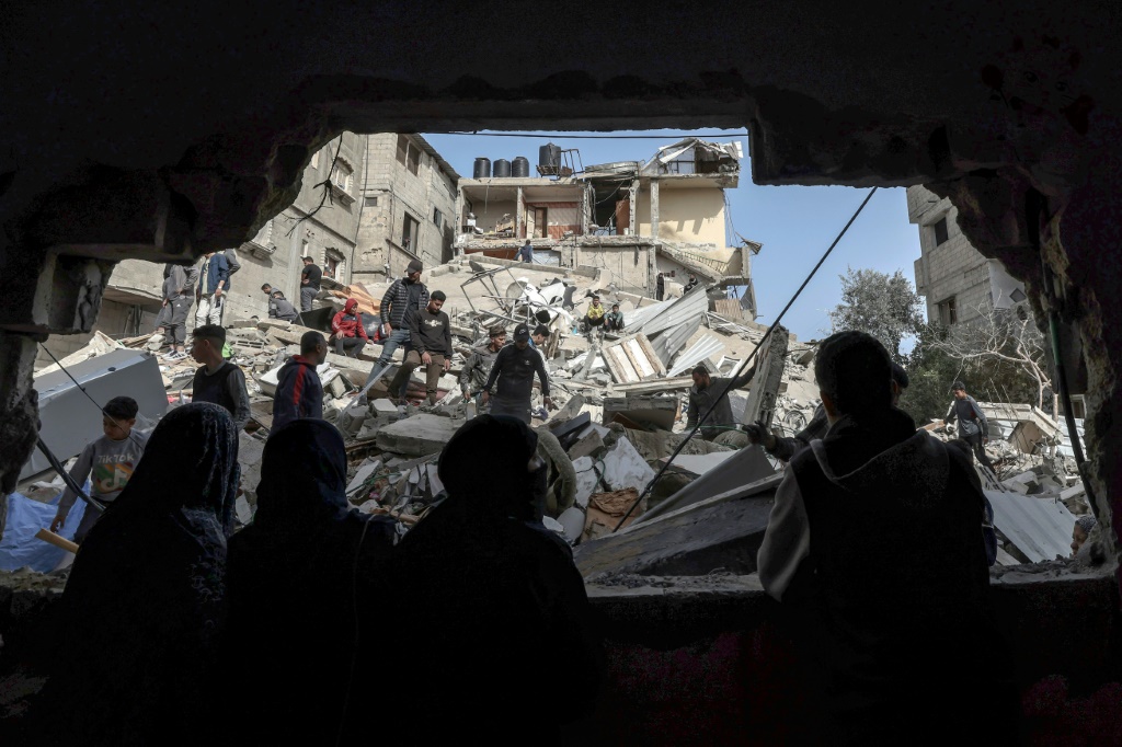 فلسطينيون يتفقدون انقاض أبنية دمّرها قصف ليلي في رفح في جنوب قطاع غزة في 27 آذار/مارس 2024 (ا ف ب)