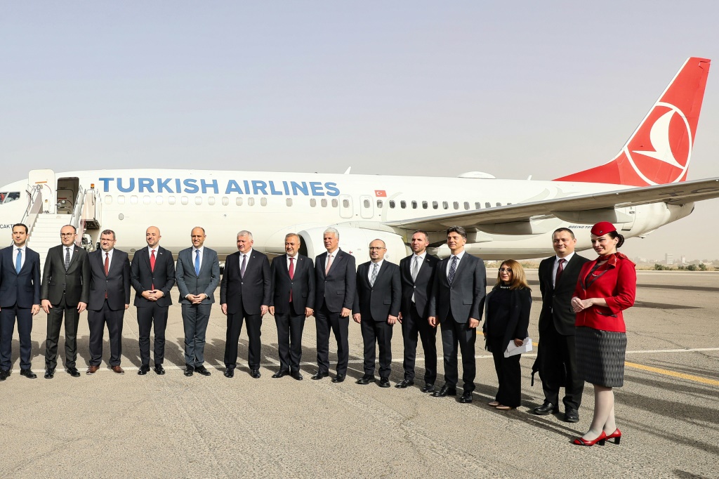 مسؤولون ليبيون وأتراك يقفون أمام طائرة تابعة للخطوط الجوية التركية، بعد هبوطها في مطار معيتيقة الدولي في طرابلس في 28 آذار/مارس 2024 (ا ف ب)