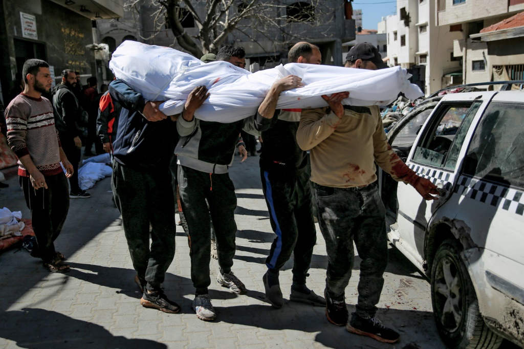 رجال يحملون جثة فلسطيني قُتل مع أكثر من مئة شخص خلال التدافع وعندما فتحت القوات الإسرائيلية النار على حشود اقتربت من شاحنات مساعدات عند نقطة توزيع في مدينة غزة في 29 شباط فبراير 2024 (ا ف ب)