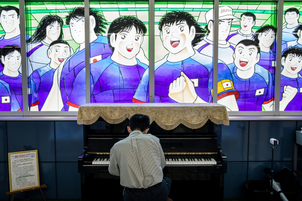 راكب قطار بجانب زجاجية عليها رسم مستوحى من سلسلة "الكابتن تسوباسا" في مجطة بمنطقة سايتاما اليابانية في الرابع من تموز/يوليو 2020 (ا ف ب)