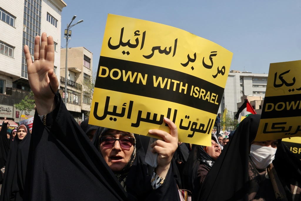 إيرانيون يتظاهرون رافعين أعلاما فلسطينية وإيرانية ولافتات كتب عليها "الموت لإسرائيل" بعد صلاة الجمعة في 19 نيسان/أبريل 2024 في طهران (أ ف ب)   