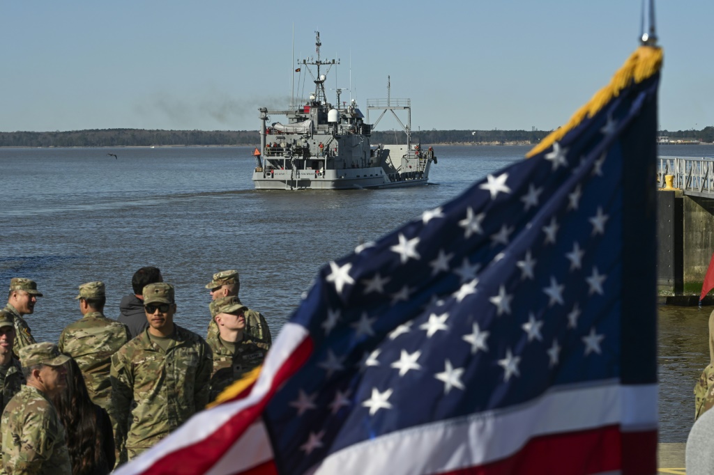 جنود من الجيش الأمريكي يقفون بالقرب من العلم الأمريكي بينما تغادر سفينة USAV Wilson Wharf للقيام بعملية لبناء ميناء مؤقت على ساحل غزة لتوصيل المساعدات المطلوبة بشكل عاجل. (ا ف ب) 