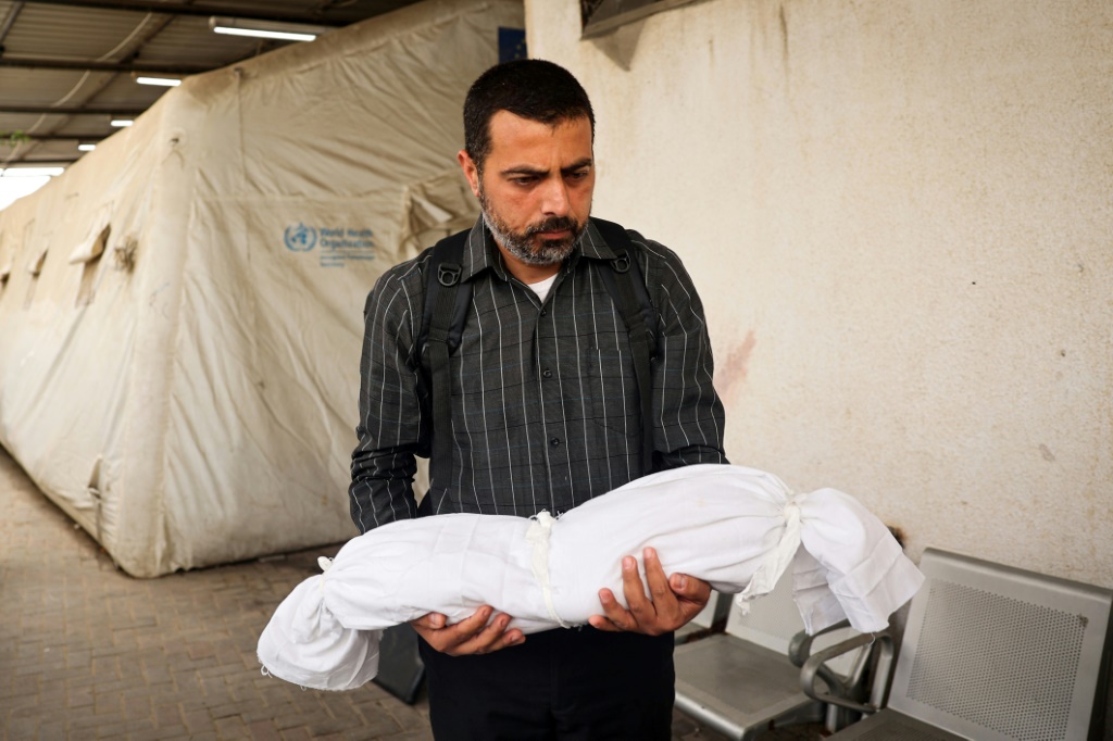 رجل يحمل جثة طفل بعد غارة إسرائيلية على مدينة رفح التي تعهدت إسرائيل بغزوها (ا ف ب)