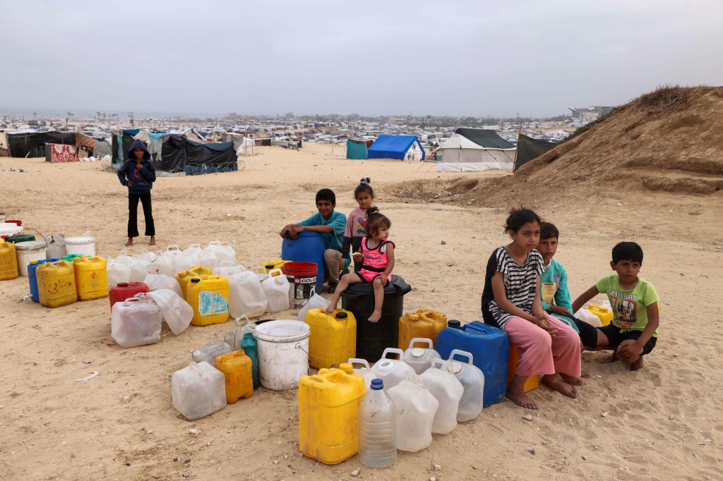 أطفال فلسطينيون نازحون ينتظرون الحصول على الماء في مخيمهم في رفح - تقدر وكالة الأمم المتحدة للطفولة أن الحرب أدت إلى نزوح حوالي 850 ألف طفل في غزة (أ ف ب)   