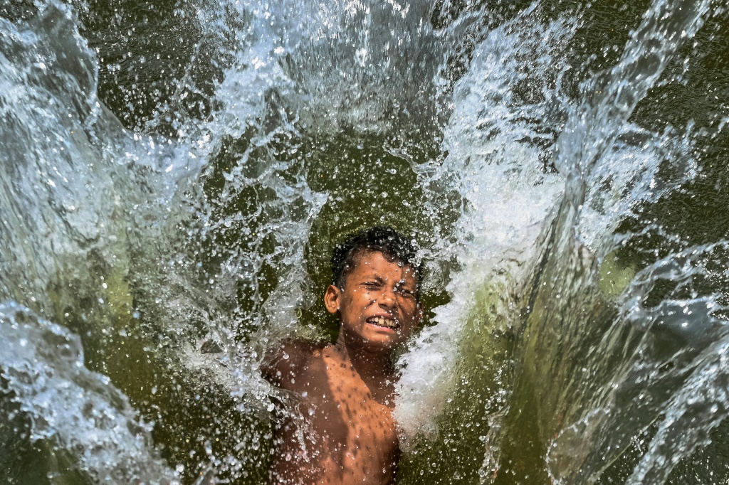 طفل يغطس في بحيرة هربا من الحرارة الشديدة في دكا في 29 نيسان/أبريل 2024 (ا ف ب)