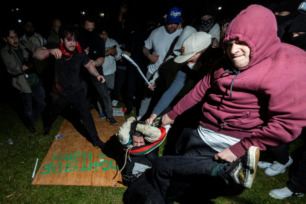 صورة مؤرخة في 1 أيار/مايو لمتظاهر مؤيد للفلسطينيين يبرَّح ضربا على يدي محتج مناهض له في جامعة كاليفورنيا في لوس أنجليس
