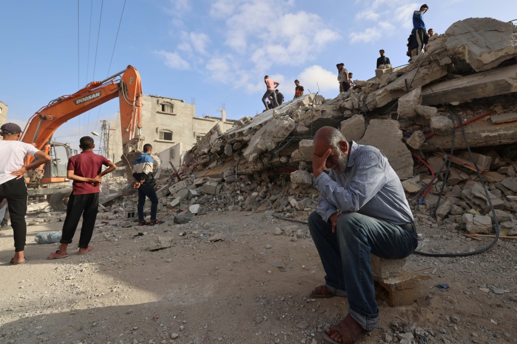 أحد سكان غزة ينتظر أخبارًا عن ابنته بينما يبحث عمال الإنقاذ عن ناجين تحت أنقاض مبنى مدمر في رفح (ا ف ب)