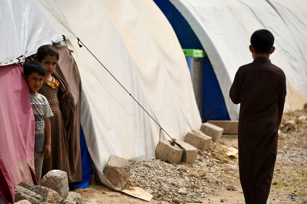 أطفال يقفون بجانب الخيام في نيسان/أبريل 2024 في مخيم الجدعة جنوب الموصل الذي يأوي عائلات عراقية عادت من مخيم الهول في سوريا (أ ف ب)   