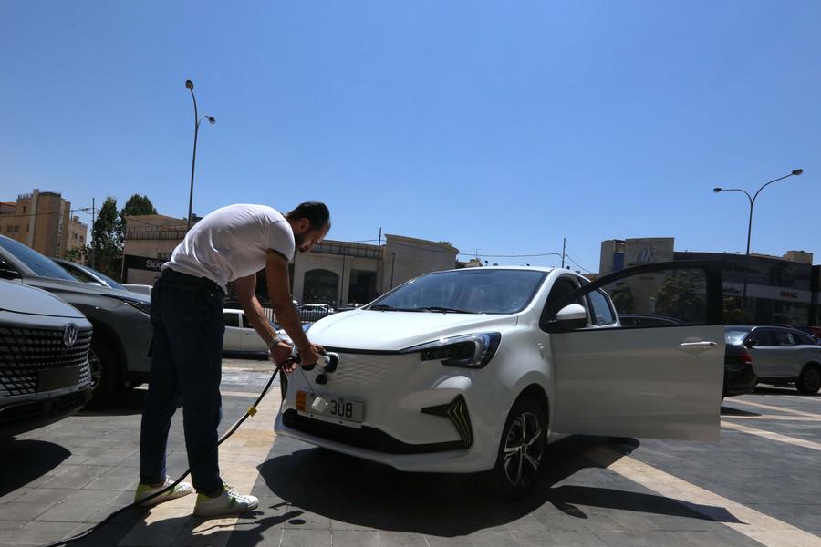 مدير مبيعات يقوم بشحن سيارة كهربائية من إنتاج شركة تشانغآن الصينية لصناعة السيارات في مركز لأحد وكلاء بيع السيارات في عمان بالأردن، 15 أغسطس 2022 (شينخوا)