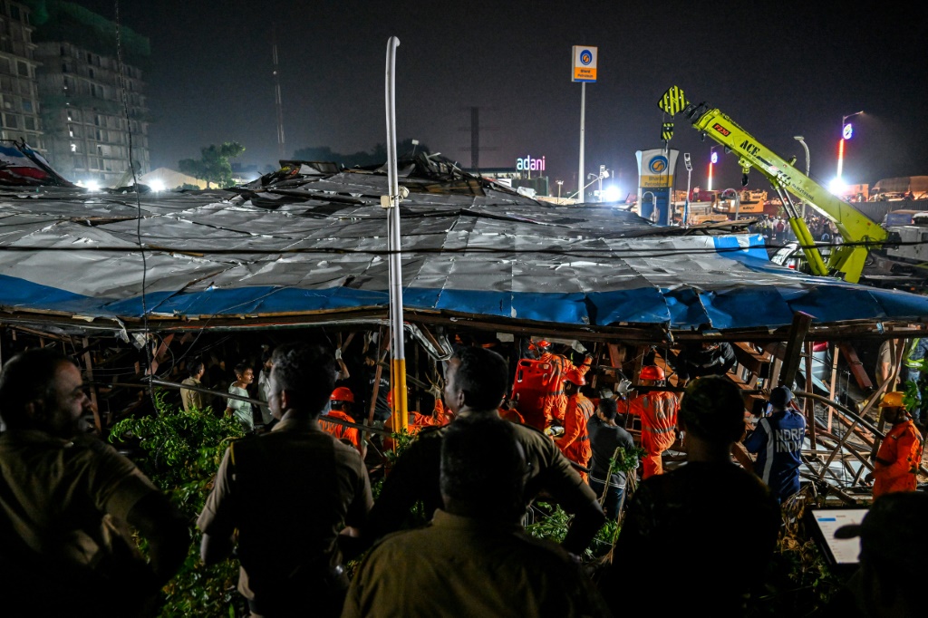 يبحث أفراد القوة الوطنية للاستجابة للكوارث (NDRF) عن ناجين أثناء عملية الإنقاذ في الموقع حيث انهارت لوحة إعلانية على محطة وقود بعد عاصفة ترابية في مومباي في 13 مايو 2024 (ا ف ب)