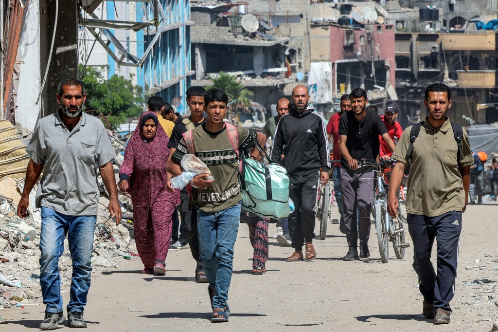 فلسطينيون يسيرون في 14 أيار/مايو 2024 وسط ابنية مدمرة في أحد شوارع جباليا في شمال قطاع غزة (أ ف ب)   