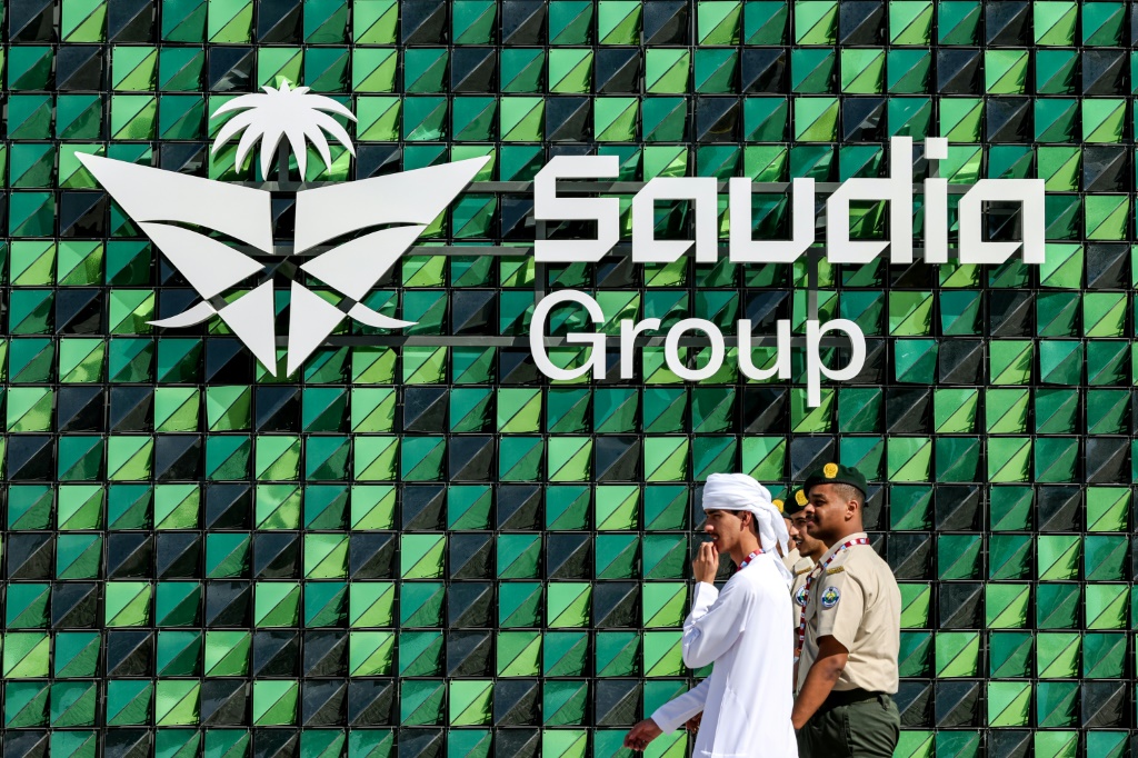 زوار يمرون أمام شعار شركة الخطوط الجوية السعودية خلال معرض دبي الدولي للطيران 2023 في مطار ال مكتوم الدولي في دبي في 13 تشرين الثاني/نوفمبر 2023 (أ ف ب)   