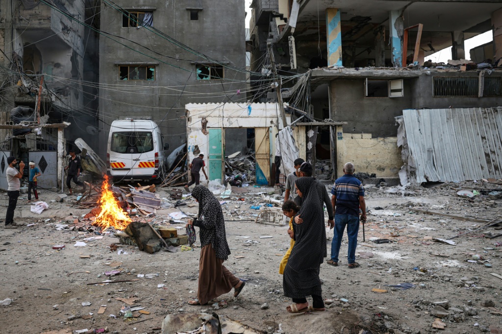 فلسطينيون ينظرون إلى أنقاض منزل عائلة تعرض للقصف الإسرائيلي في رفح جنوب قطاع غزة (ا ف ب)