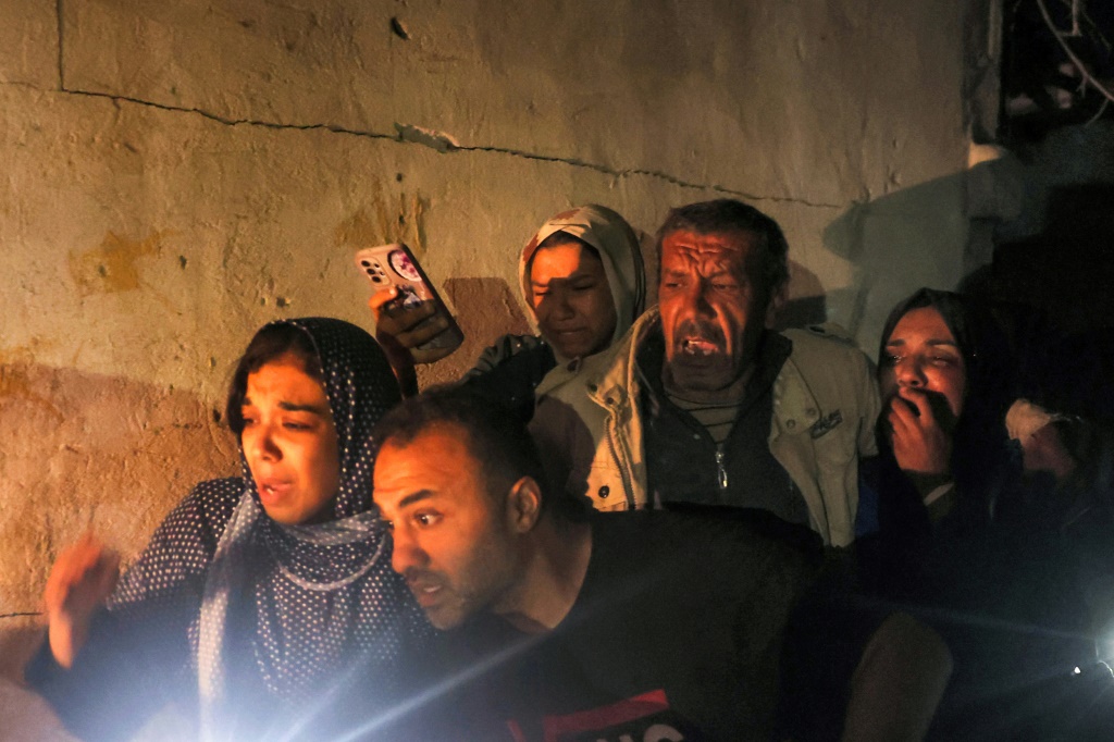 أفراد عائلة يتجمعون حول قريب جريح بينما تساعد فرق الدفاع المدني في إنقاذ الضحايا من منزل تعرض للقصف الإسرائيلي في رفح (ا ف ب)
