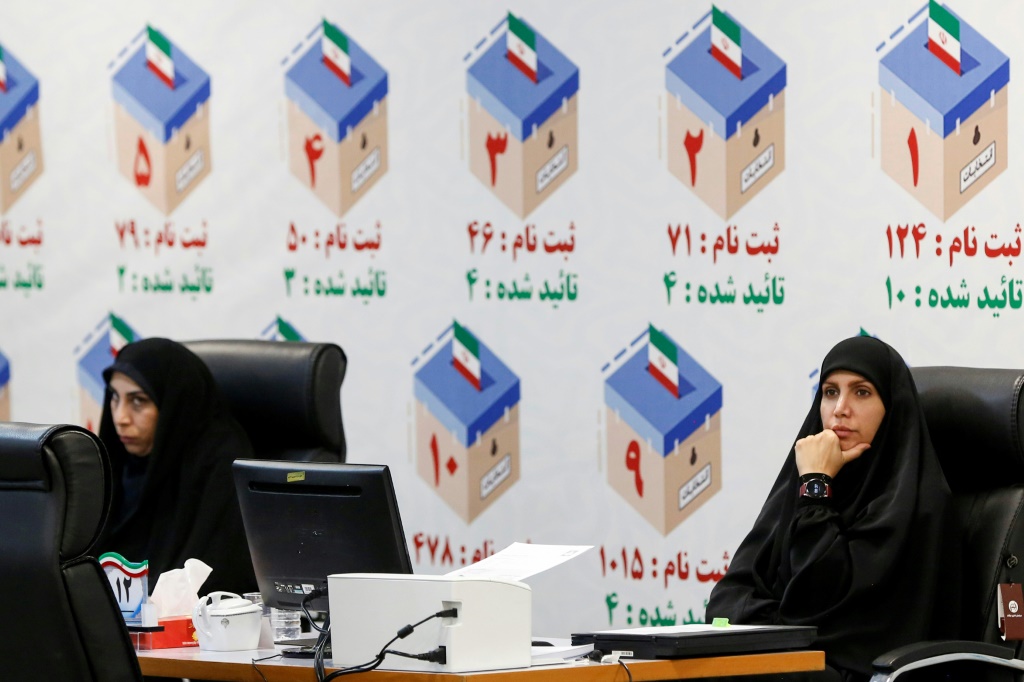 مسؤولو الانتخابات الإيرانيون في مكتب التسجيل في طهران قبل الانتخابات المبكرة بعد وفاة إبراهيم رئيسي (ا ف ب)