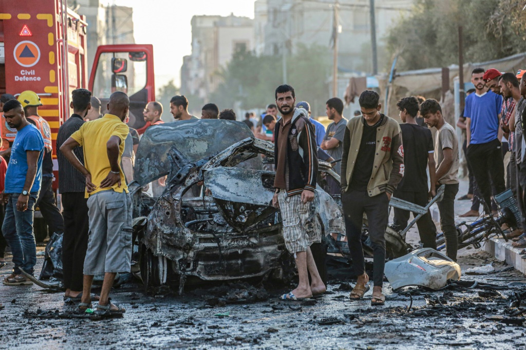 فلسطينيون يتفقدون مركبة محترقة بعد غارة إسرائيلية على وسط قطاع غزة (ا ف ب)