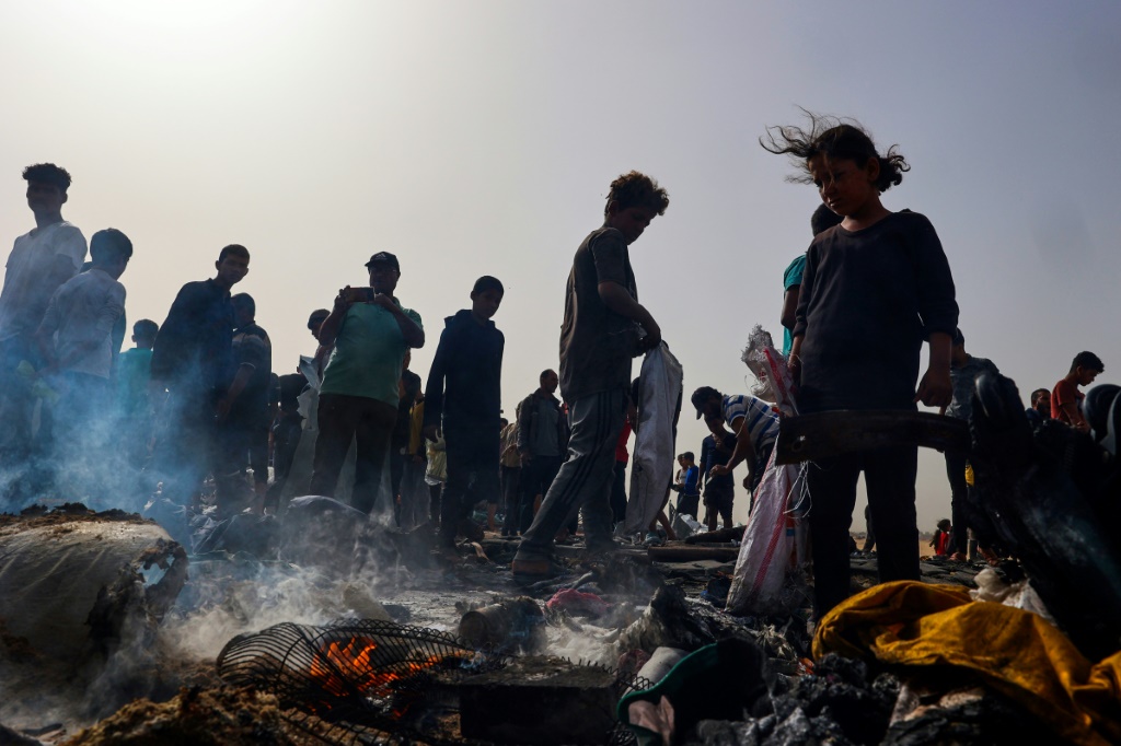   فلسطينيون يتجمعون في موقع غارة إسرائيلية على منطقة مخيم يأوي نازحين في رفح، 27 مايو، 2024. (أ ف ب)