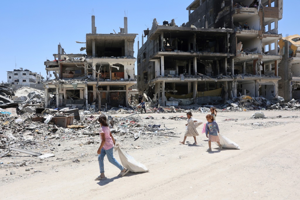 أطفال فلسطينيون يسيرون بجوار المباني المدمرة في مخيم جباليا للاجئين شمال قطاع غزة (ا ف ب)