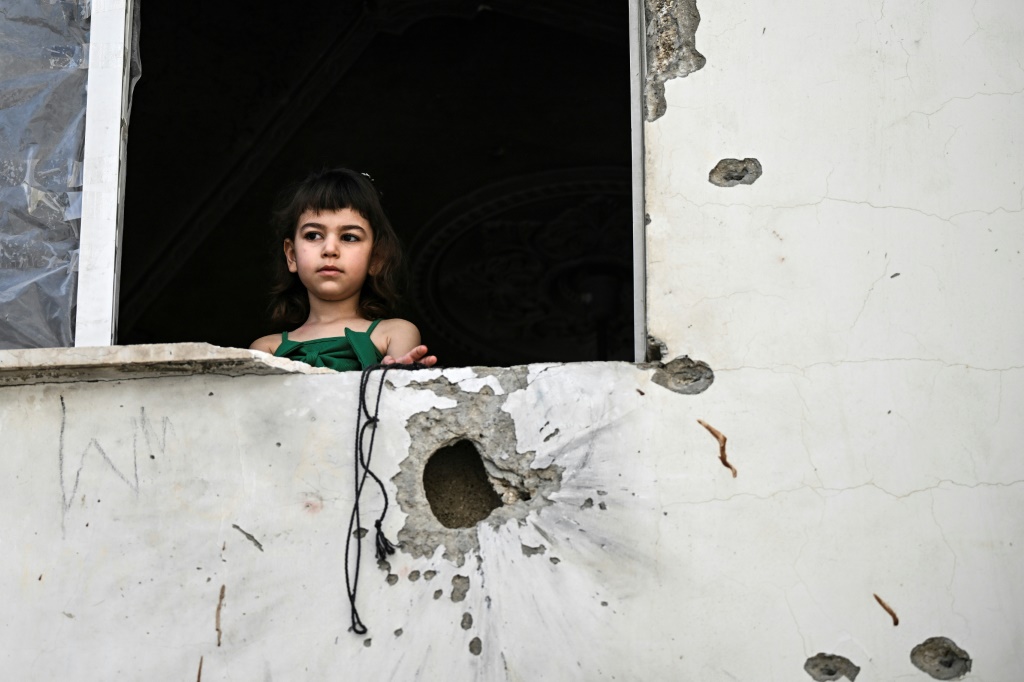طفلة فلسطينية تطل من نافذة مبنى أصيب بشظايا بعد عملية اقتحام للقوات الإسرائيلية استهدفت جنين بتاريخ 23 أيار/مايو 2024 (ا ف ب)