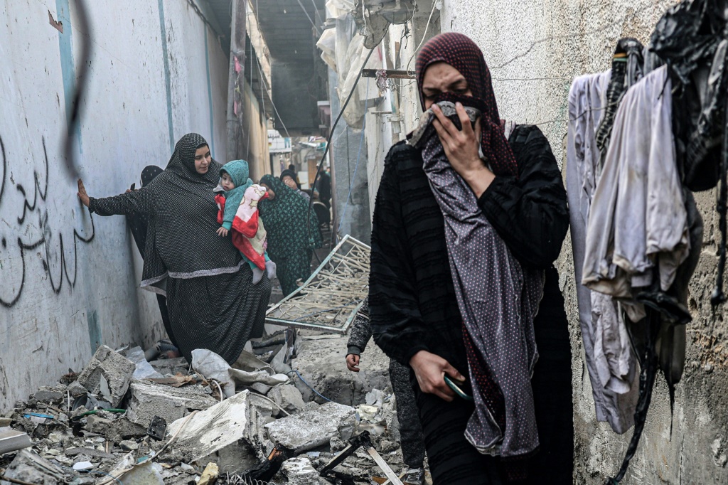 أشخاص يتحركون عبر زقاق مليء بالأنقاض في أعقاب القصف الإسرائيلي ليلاً على رفح في جنوب قطاع غزة في 25 فبراير 2024 (ا ف ب)