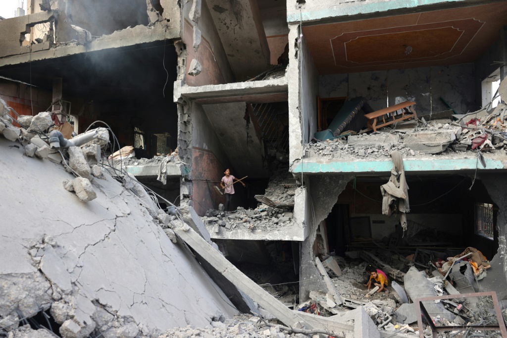 أطفال فلسطينيون يفتشون بين أنقاض منزلهم في وسط قطاع غزة في العاشر من حزيران/يونيو 2024 غداة العملية الخاصة التي نفذتها القوات الإسرائيلية في مخيم النصيرات وحررت خلالها أربعة رهائن (ا ف ب)